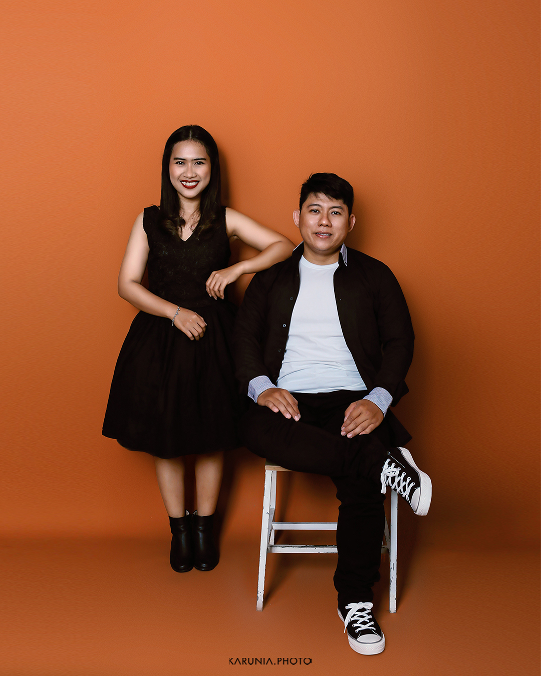 Engagement couple laughing while running through a field of wildflowers at sunset